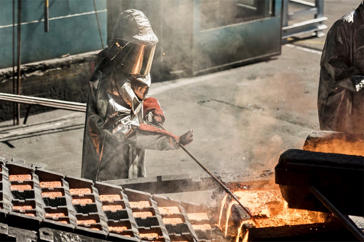 Bild Person in Schutzkleidung vor heissem Metall