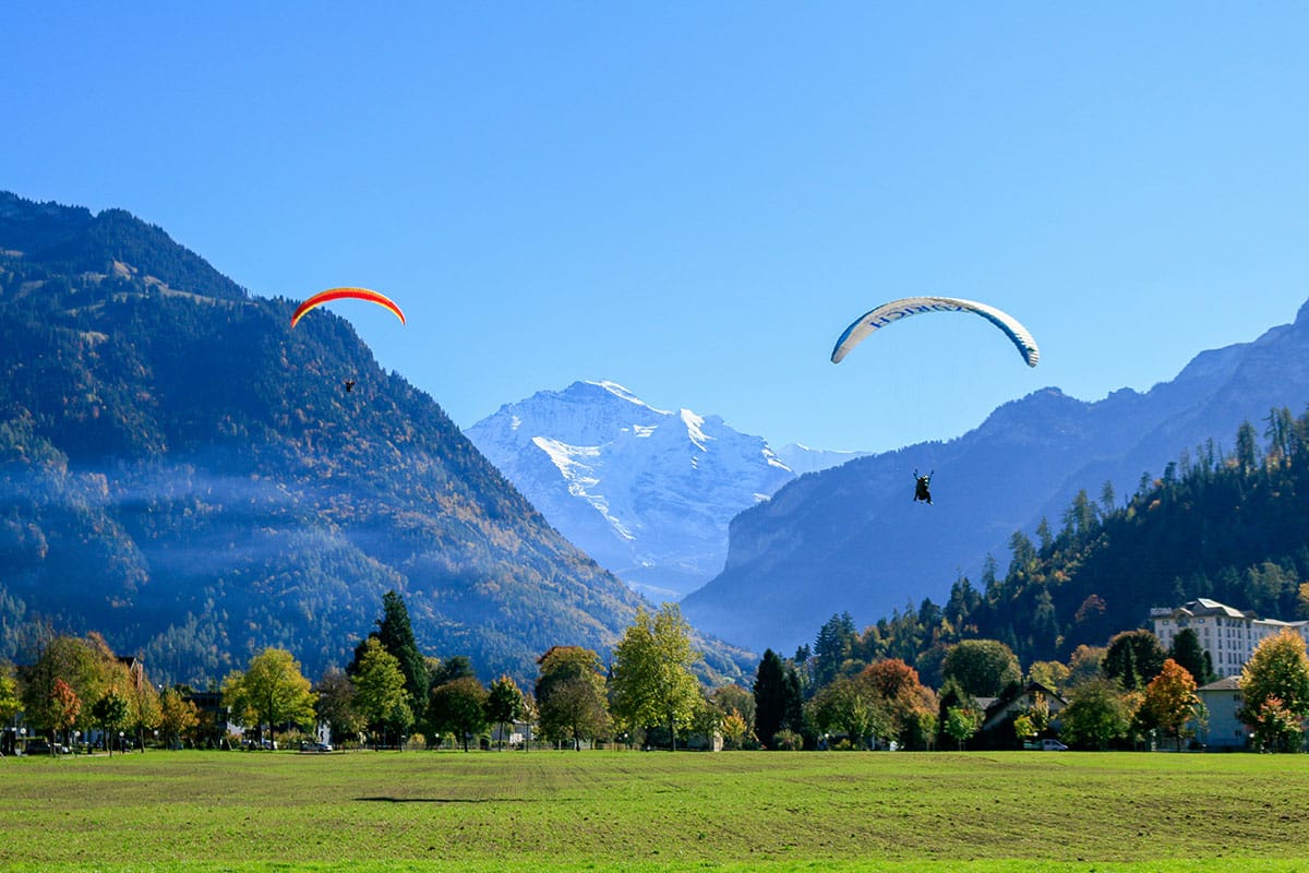 Zwei Gleitschirme, die auf der Höhematte in Interlaken landen, im Hintergrund die Jungfrau.